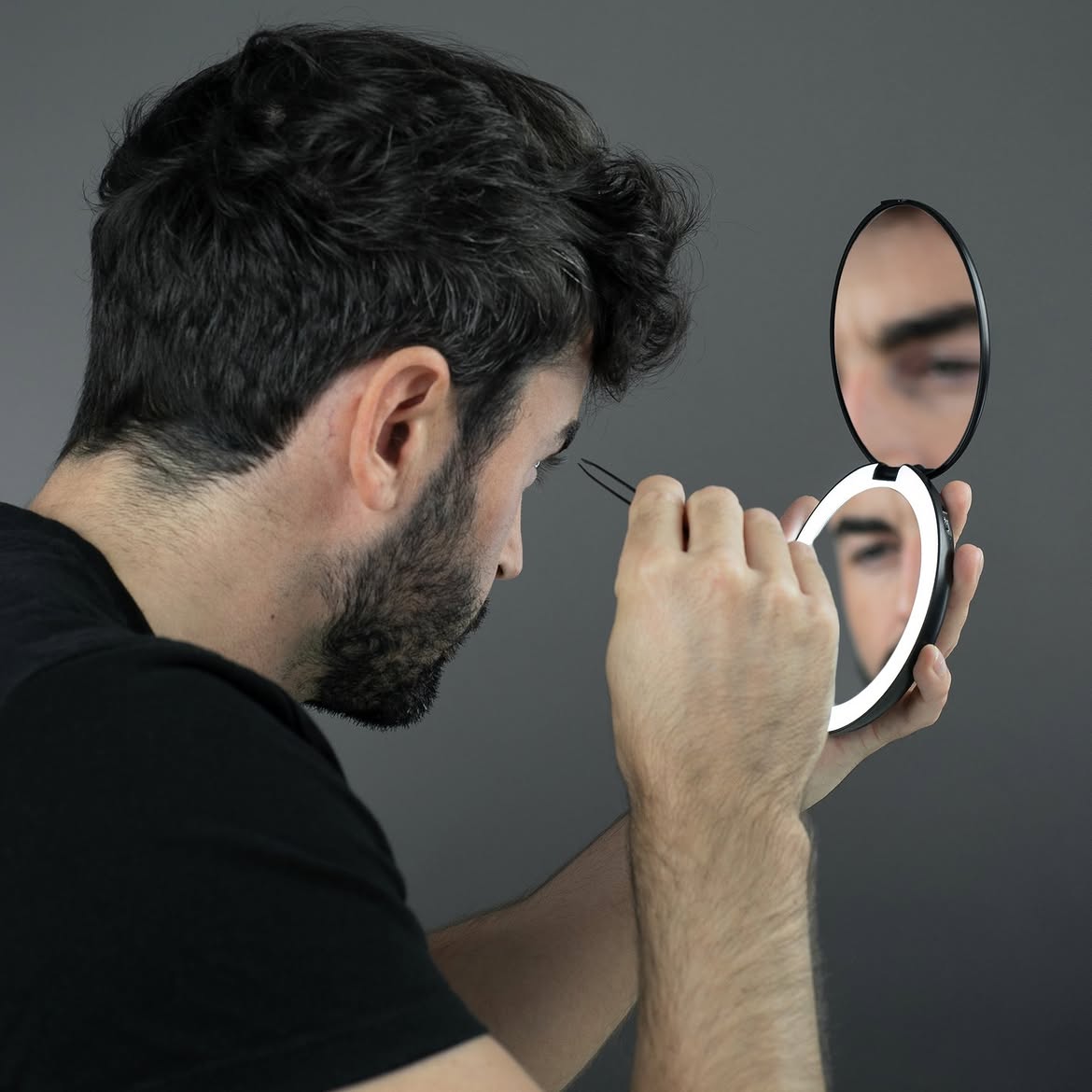 Un homme épile ses sourcils avec précision grâce au miroir grossissant COMPACT 2.0